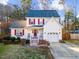 Attractive two-story home featuring red shutters, a cozy front porch, attached garage, and well-maintained lawn at 409 Machost Dr, Garner, NC 27529