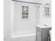 Bright bathroom featuring a shower, tub, gray vanity, and window at 415 Estell St, Rocky Mount, NC 27803