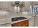 Close-up of a stove with granite countertops, stylish cabinetry, and a modern range hood at 45 Calabria Ct, Clayton, NC 27527