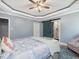 Bright bedroom with a tray ceiling, a fan, and a decorative teal barn door leading to the bathroom at 49 Everwood Dr, Four Oaks, NC 27524