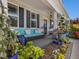 Inviting front porch featuring a comfortable seating area with a wicker couch and stylish blue planters at 49 Everwood Dr, Four Oaks, NC 27524