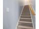 Carpeted staircase with wooden handrail leads to the upper level of the home at 49 Everwood Dr, Four Oaks, NC 27524