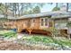 Backyard featuring a wooden deck, natural stone elements, and green lawn at 500 W Woodcroft Pkwy, Durham, NC 27713