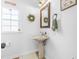 Charming powder room with pedestal sink, decorative mirror, and natural light from the window at 504 W Brocklyn St, Benson, NC 27504