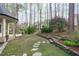 Lush backyard with stepping stones, mature trees, and garden beds at 506 Rose Point Dr, Cary, NC 27518