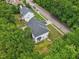 Aerial view of a two-story home with dark roof amid lush green trees and a quiet street at 5144 Pinehall Wynd, Raleigh, NC 27604