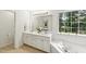 Bright bathroom with a double sink vanity, large mirror, soaking tub, and outside view at 5144 Pinehall Wynd, Raleigh, NC 27604