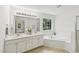 Bright bathroom with double sink vanity, a large mirror, and a tub under a window at 5144 Pinehall Wynd, Raleigh, NC 27604