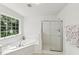 Sunlit bathroom with a glass door shower and a large soaking tub by the window at 5144 Pinehall Wynd, Raleigh, NC 27604