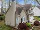 Side view of a tan home with dark brown roof, manicured landscaping, and a view of the garage at 5301 Tilford Ln, Raleigh, NC 27613