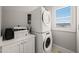 Convenient laundry area with stacked washer and dryer units, storage cabinets, and natural light at 605 Smedes Pl # A, Raleigh, NC 27605