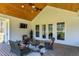 Covered outdoor patio featuring a brick floor, comfortable seating, ceiling fan, and mounted television at 6480 Beaver Creek Rd, New Hill, NC 27562