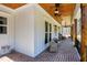 Long, covered porch showcasing brick floors, ceiling fans, and cozy wicker seating at 6480 Beaver Creek Rd, New Hill, NC 27562