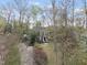 An aerial view captures a brick home nestled amongst mature trees, with a neatly manicured lawn and driveway at 721 Blenheim Dr, Raleigh, NC 27612