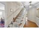 Inviting hallway with carpeted stairs, a wooden handrail, and an elegant chandelier, leading to hardwood floors at 721 Blenheim Dr, Raleigh, NC 27612