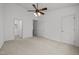 A large bedroom with neutral carpeting, a ceiling fan, and multiple doors at 7628 Winners Edge St, Raleigh, NC 27617