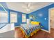 Bright bedroom with vibrant blue walls, hardwood floors, and two windows at 765 Carlton St, Clayton, NC 27520