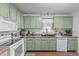 Well-lit kitchen with green cabinets, modern appliances, and functional layout with neutral flooring at 900 Stoneybrook Dr, Sanford, NC 27330