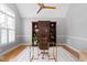 A well-lit home office with a glass desk, custom built-ins, and hardwood floors at 9320 Teton Pines Way, Raleigh, NC 27617