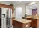 Well-equipped kitchen features an island, stainless steel refrigerator, granite countertops, and wooden cabinetry at 1008 Garden Square Ln, Morrisville, NC 27560
