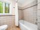 Clean bathroom with tiled walls, a shower-tub combo, a window view, and a neutral color palette at 109 Barcliff Ter, Cary, NC 27518