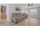Living room with a plush gray sofa, showcasing modern flooring, and a ceiling fan at 125 Camden Dr, Youngsville, NC 27596
