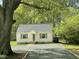 Quaint yellow home featuring a grey roof, blue shutters, and mature trees, creating a welcoming curb appeal at 1306 Ed Cook Rd, Durham, NC 27703