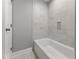 Close up of a bathtub and shower tiled with marble-style tile at 1426 Quarter Pt, Raleigh, NC 27615