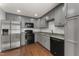 Well-lit kitchen features gray cabinets, granite counters, stainless steel fridge, and dark appliances at 1426 Quarter Pt, Raleigh, NC 27615