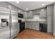 Modern kitchen features gray cabinets, stainless steel refrigerator, black appliances, and hardwood floors at 1426 Quarter Pt, Raleigh, NC 27615