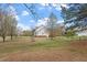 Spacious backyard featuring mature trees and a charming view of the property with an outbuilding and a fenced area at 15 Longwood Dr, Youngsville, NC 27596