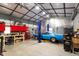 The metal building has an automotive lift and tools surrounding a blue car at 15 Longwood Dr, Youngsville, NC 27596