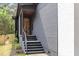 Home exterior featuring modern gray siding, black railing, wood door, and brick accents at 1621 Bruce Circle, Raleigh, NC 27604