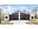 Modern duplex featuring a gray and white exterior, black garage doors, and a concrete driveway and walkway at 1625 Bruce Circle, Raleigh, NC 27604