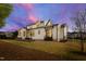 The backyard features a modern white home with a patio area, and a vibrant sky at dusk at 1629 Montvale Grant Way, Cary, NC 27519