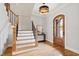 Elegant foyer with hardwood floors, a grand staircase, eye-catching light fixture, and decorative front door at 1629 Montvale Grant Way, Cary, NC 27519