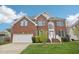 Two-story brick home with blue shutters, manicured lawn, and attached two car garage at 1903 Yellowwood Ln, Durham, NC 27712