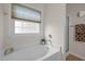 A bathroom featuring a soaking tub under a window and a separate shower at 203 Grassy Point Rd, Apex, NC 27502