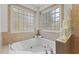 A white tiled bath with a large soaking tub under glass block windows at 219 Arbordale Ct, Cary, NC 27518
