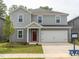 Charming two-story home with gray siding, a red front door, a manicured lawn, and an attached two-car garage at 2206 Cherry Creek Rd, Haw River, NC 27258