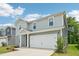 Charming two-story home featuring gray siding, a red front door, an attached garage, and landscaped front yard at 2206 Cherry Creek Rd, Haw River, NC 27258