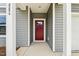 Close-up of the red front door with glass panel, set within a gray-sided home and framed by white pillars at 2206 Cherry Creek Rd, Haw River, NC 27258