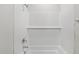 Clean white tiled bathtub and shower with modern fixtures, and a shelf at 2211 Cherry Creek Rd, Haw River, NC 27258