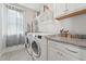 Bright laundry room with granite countertops, white cabinetry, and modern washer and dryer at 233 Airlie Dr, Chapel Hill, NC 27516
