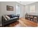 Cozy sitting room featuring hardwood floors, a comfortable sofa, and natural light from two windows at 233 Airlie Dr, Chapel Hill, NC 27516