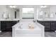 Bright primary bathroom with tiled floor, soaking tub between dual vanities, and natural light from a centered window at 237 Begen St, Morrisville, NC 27560