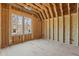Bedroom with wood framing and large windows offering natural light, awaiting drywall and finishing touches at 2605 Hazelwood Dr, Raleigh, NC 27608