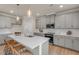 Kitchen boasts stainless steel appliances, gray cabinets, tile backsplash, quartz countertop island with pendant lights, and seating at 279 Providence Creek Dr, Fuquay Varina, NC 27526