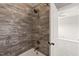 A white bathtub and shower featuring grey marble style tiling with a bronze faucet and shower head at 2936 Turning Brook Ln, Raleigh, NC 27616