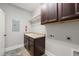 This laundry room features dark brown cabinets, a utility sink with a granite countertop and a white shelf at 2936 Turning Brook Ln, Raleigh, NC 27616